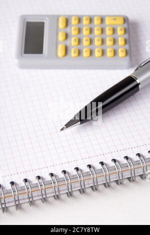 business concept - close up of note book with checked pages, pen and calculator Stock Photo