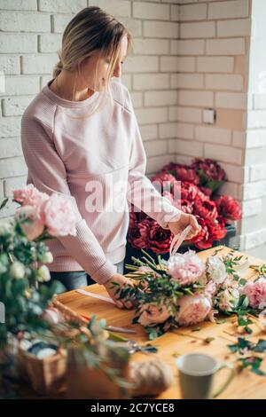 hands of florist against desktop with working tools and ribbons on wooden background Stock Photo
