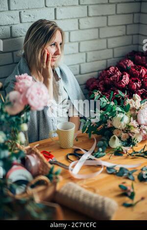 Smiling Mature Woman Florist Small Business Flower Shop Owner. She is using her telephone to take orders for her store Stock Photo