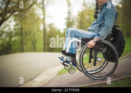 male hand on wheel of wheelchair during walk in park