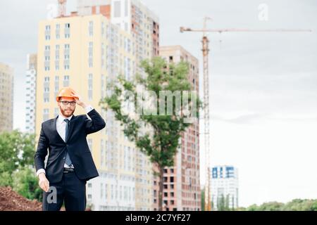 young handsome, engineer, foreman, architect builder looks at the construction of the structure, at the station, wearing a white protective helmet, sm Stock Photo