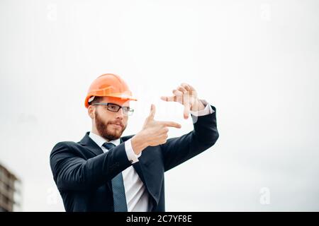 senior builder in hardhats pointing workers outdoors Stock Photo