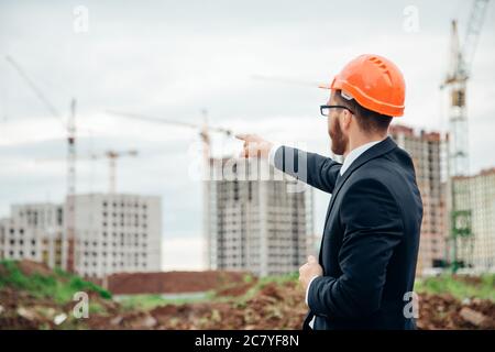 senior builder in hardhats pointing workers outdoors Stock Photo