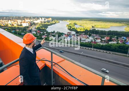 senior builder in hardhats pointing workers outdoors Stock Photo