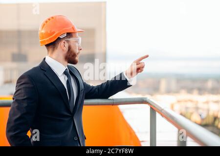 senior builder in hardhats pointing workers outdoors Stock Photo