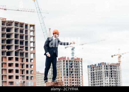 senior builder in hardhats pointing workers outdoors Stock Photo
