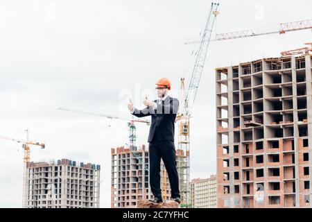 senior builder in hardhats pointing workers outdoors Stock Photo