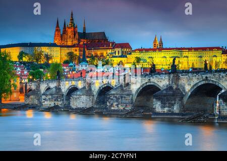 Famous Charles bridge over the Vltava river in Prague at evening. Amazing locations and majestic buildings with colorful lights after sunset, Prague, Stock Photo