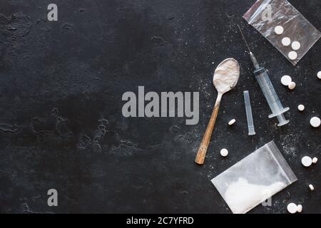 Drugs in the form of powder and tablets, a spoon and a syringe on a black background mockup Stock Photo