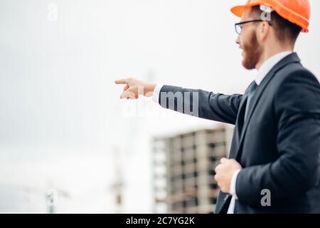 senior builder in hardhats pointing workers outdoors Stock Photo