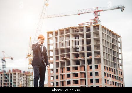 business, building, industry, technology and people concept - smiling builder in hardhat at construction site Stock Photo
