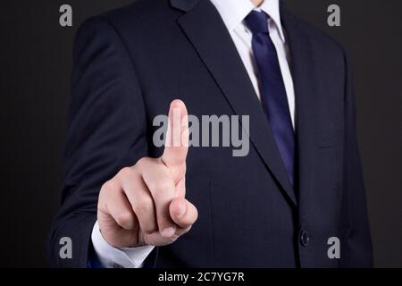 businessman hand pressing an imaginary button on over dark background Stock Photo
