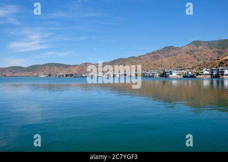 mountains and inn houses along the blue Erhai lake in Shuanglang Yunnan China. Symmetrical reflection in peaceful water. Stock Photo