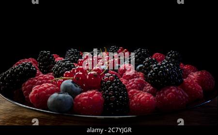 Fresh berries composition. Raspberries, blackberries, red currant and blueberries on black background. Tasty looking organic superfood Stock Photo