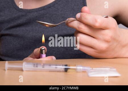addict heating heroin in a spoon over a flame Stock Photo