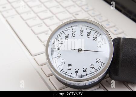 close up of sphygmomanometer on white notebook keyboard Stock Photo