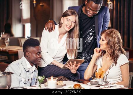 Two mixed couples having a good time at restaurant talking about future vacations Stock Photo