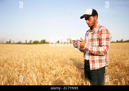 Precision farming. Farmer holding tablet pc, using online data management software at wheat field. Agronomist working with touch computer screen Stock Photo