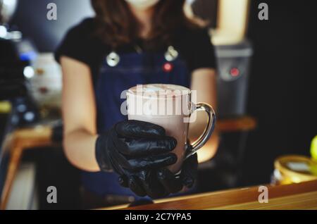 Barista wearing medical latex black gloves, making pink matcha latte with milk.Bartender preparing tasty drink Stock Photo