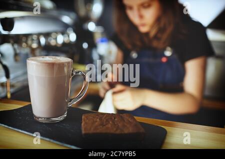 Barista making pink matcha latte with milk. Bartender preparing tasty drink and brownie cake Stock Photo