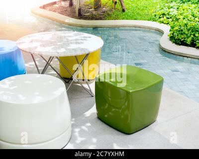Modern bright colors chairs and a variety of shapes and round tables beside the outdoor swimming pool. Empty colorful furniture decoration near the po Stock Photo