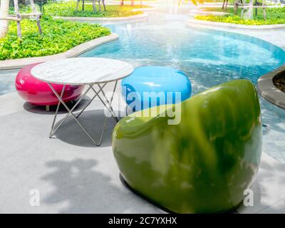 Modern bright colors chairs and a variety of shapes and round tables beside the outdoor swimming pool. Empty colorful furniture decoration near the po Stock Photo
