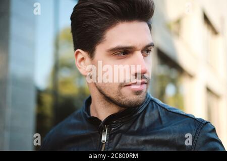 Portrait of young attractive man thoughtfully looking away outdoor Stock Photo