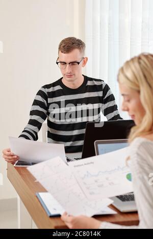 Young couple working with financial documents at table when staying home due to coronavirus pandemic Stock Photo