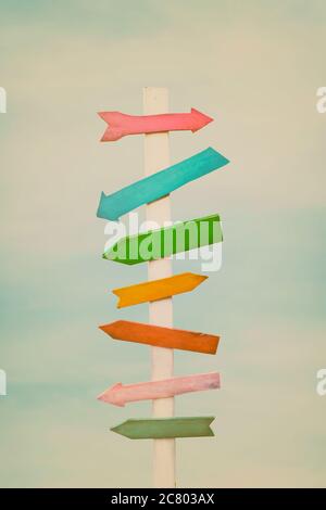Colorful wooden direction arrow signs on a wooden pole Stock Photo