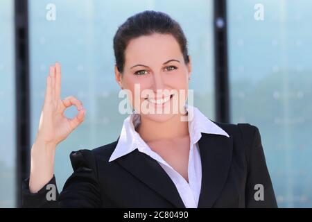 young business woman in black suit showing ok outside Stock Photo