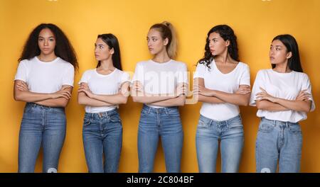Diverse Women Looking At African Girl Standing Over Yellow Background Stock Photo