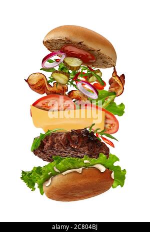 Big burger with flying ingredients isolated on white. Ham, beef cutlet, cheese, mayonnaise, ketchup, vegetables and greens. Close up, copy space Stock Photo