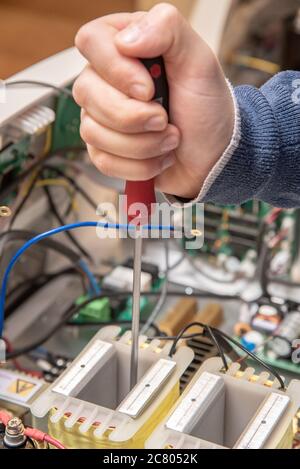 Hands of an Technician holding a screwdriver as he fixes an electronics device Stock Photo