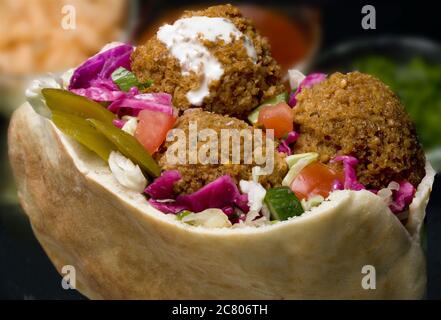 Falafel in pita bread with salad and Tahini sauce. Fried balls of patty made from spiced chickpeas. falafel is a popular form of fast food in the Midd Stock Photo