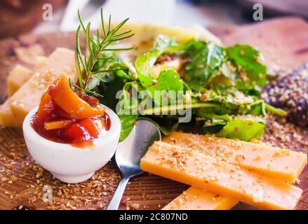 A variety of cheeses served with sweet tomato and orange sauce, herbs and seeds, selective focus Stock Photo