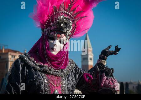 VENICE, ITALY - 28 FEBRUARY 2019: a purple dame costume during Venice Carnival poses with San Marco in background Stock Photo