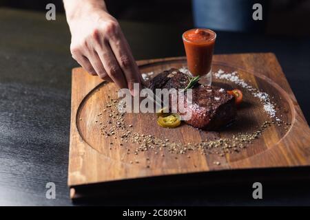 Chef sprinkling spices on dish in commercial kitchen Stock Photo
