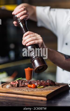 Chef sprinkling spices on dish in commercial kitchen Stock Photo