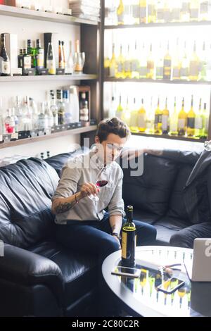 Portrait young sommelier standing at family wine cellar with senior winemaker and tasting a glass of red wine. Small business. Stock Photo