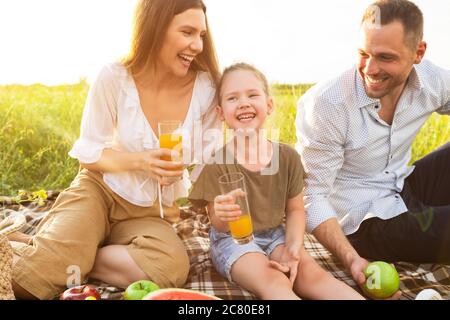 Laughing family drinking orange juice from glasses Stock Photo