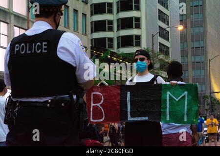 Chicago, IL, USA. 18th July, 2020. A young person holds up a sign in front of a Chicago police commander during a protest on Michigan Ave. in Chicago on July 18, 2020. Credit: Dominic Gwinn/ZUMA Wire/Alamy Live News Stock Photo