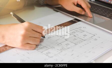 Engineers holding a pen pointing to a building and using laptop to planning project schedule. Engineering and construction concept. Stock Photo