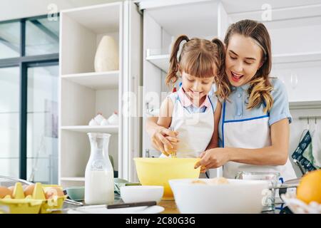 Happy mother and daughter spending weekend together and making pancakes for breakfast Stock Photo