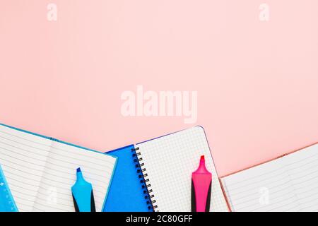 Back to school concept. Notepads and felt tip pens on pastel pink backdrop. Copy space for text, top view Stock Photo