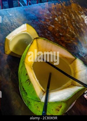 Sweet green coconuts water with drinking straw on table. Coconut tropical fruit in Koh Samui, PhaNgan and koh tao , surat thani and chumphon at Bali Stock Photo