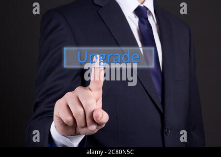 businessman hand pressing upgrade button over dark background Stock Photo