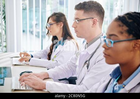 Concentrated young laboratory workers entering results of research in computers Stock Photo