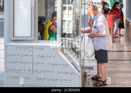 Punta Umbria, Huelva, Spain - July 11, 2020: Man in protective face mask is buying lottery tickets at a ONCE kiosk in Punta Umbria, Andalusia, Spain Stock Photo