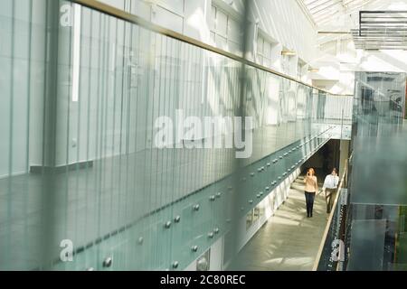 Wide angle background image of contemporary office building interior with glass and concrete, people walking on balcony, copy space Stock Photo