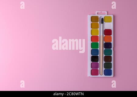 Rectangular box palette with honey colored watercolors and a brush on a pink background , top view Stock Photo